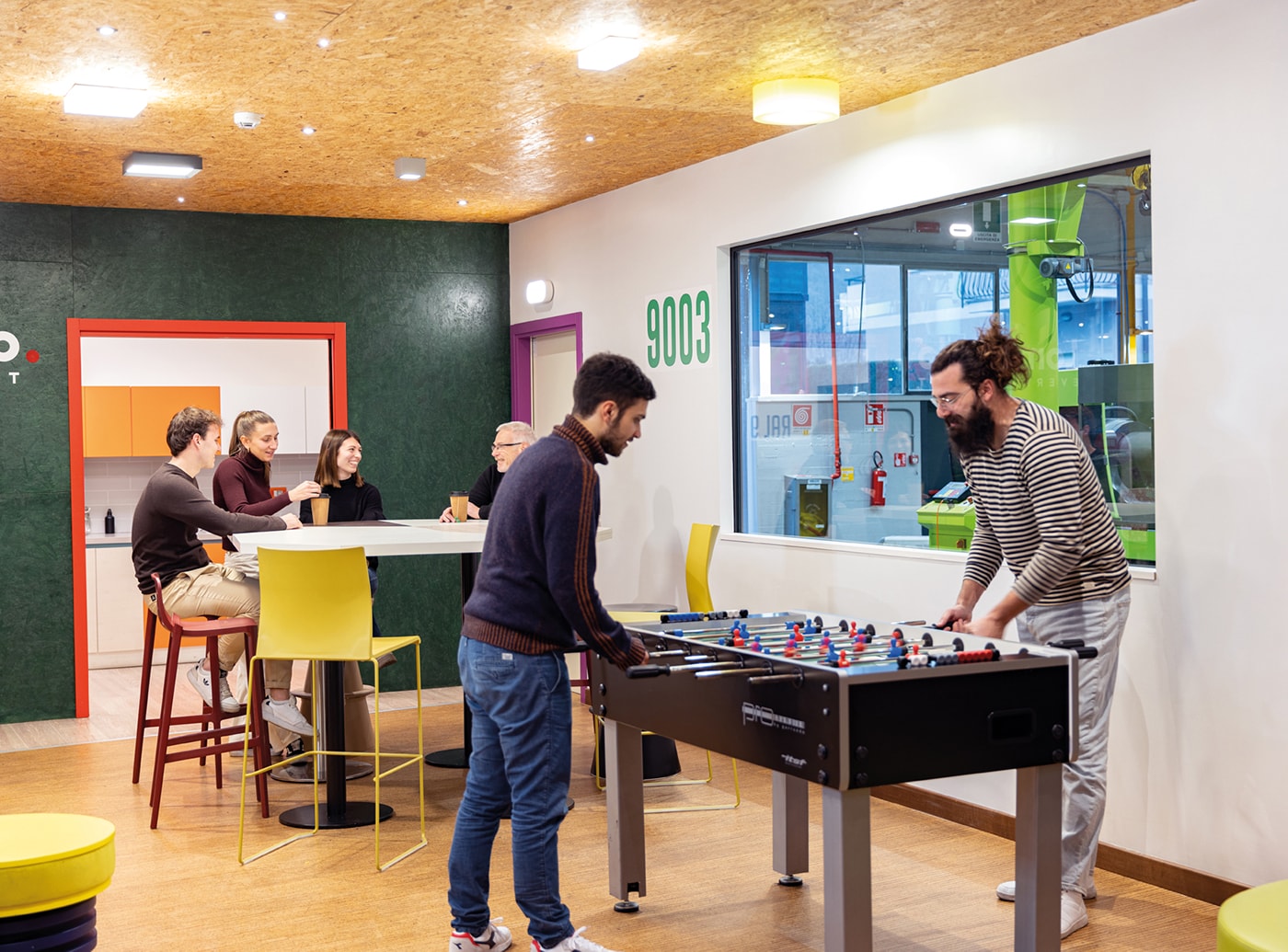 Corporate relaxation area with employees relaxing, chatting, and playing table football