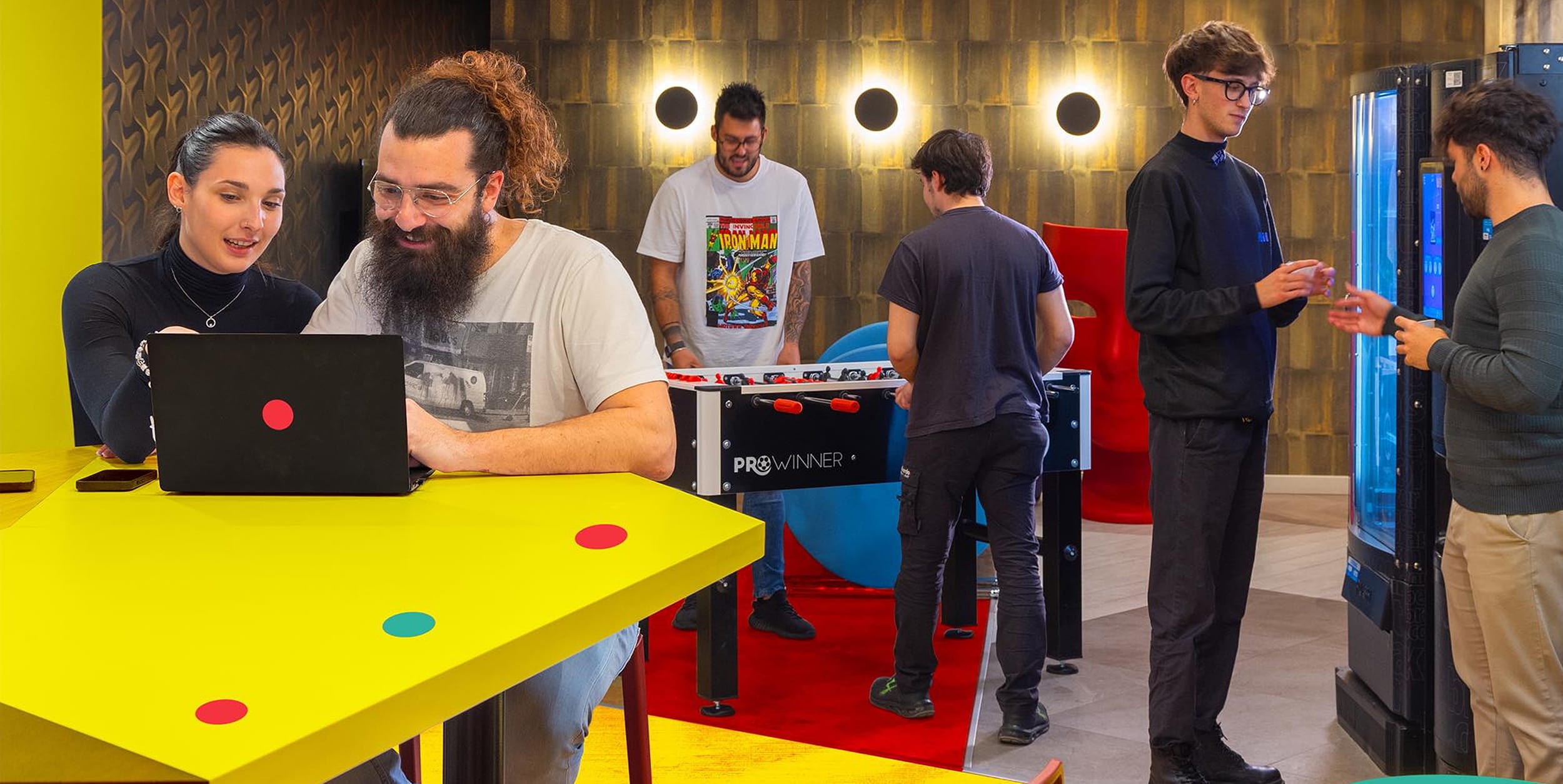 Employees collaborating, relaxing, and playing table football in the common area
